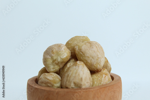 Dried Indonesian Candlenuts, or Kemiri, the seed of Aleurites moluccanus inside a wooden bowl, isolated in white background