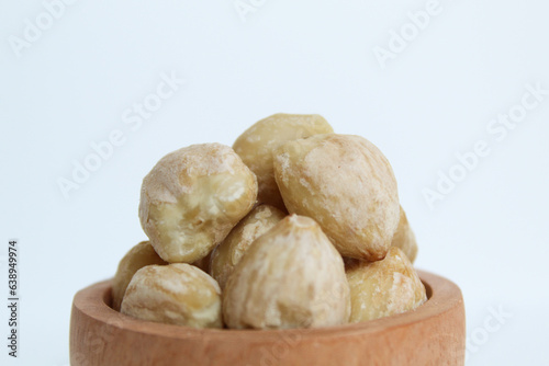 Dried Indonesian Candlenuts, or Kemiri, the seed of Aleurites moluccanus inside a wooden bowl, isolated in white background