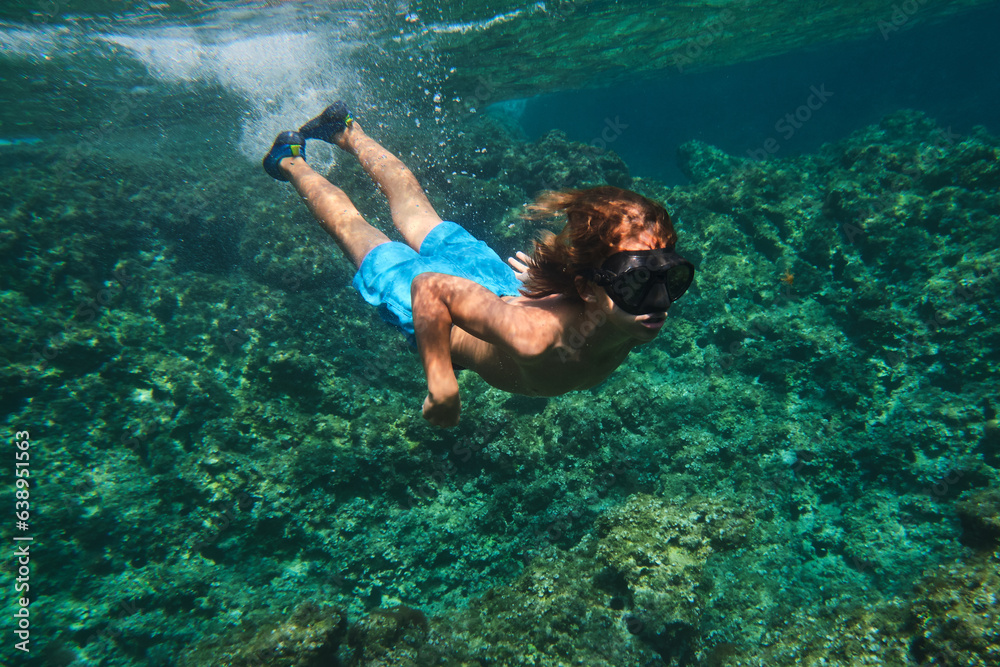 Boy in black goggles swimming underwater