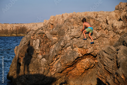 Canvas Print Boy scrambling on stony coast