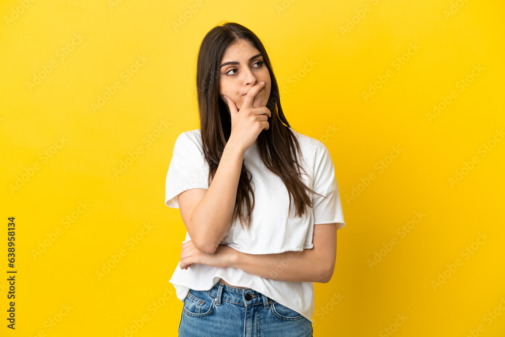 Young caucasian woman isolated on yellow background having doubts and with confuse face expression Young caucasian woman isolated on yellow background having doubts and with confuse face expression