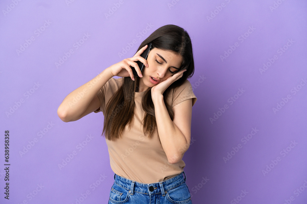 Young caucasian woman using mobile phone isolated on purple background with headache Young caucasian woman using mobile phone isolated on purple background with headache