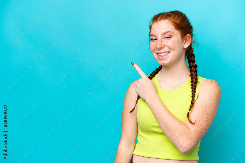 Young reddish woman isolated on blue background surprised and pointing side Young reddish woman isolated on blue background surprised and pointing side