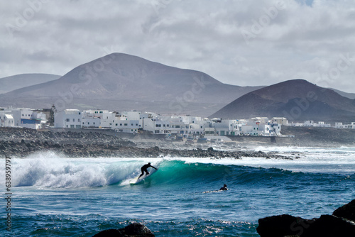     Go to Page 12345...9Next  Silhouette of a surfer on a wave of  La Santa  surf spot on the Island of Lanzarote with volcanoes and a little fishing village in the background in April 2019