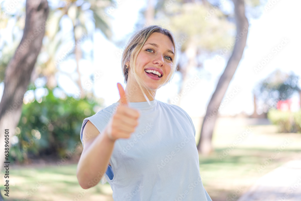 Young blonde woman at outdoors with thumbs up because something good has happened Young blonde woman at outdoors with thumbs up because something good has happened