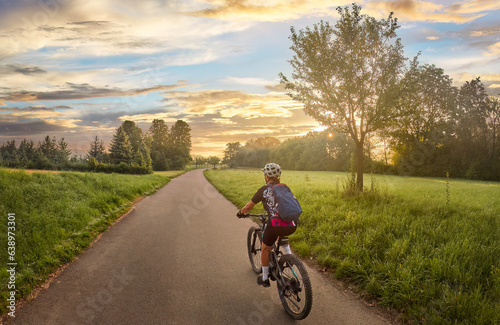 nice woman with electric mountain bike, cycling in moody morning light on the Neckar valley bicycle path near Ludwigsburg, Baden Württemberg, Germany