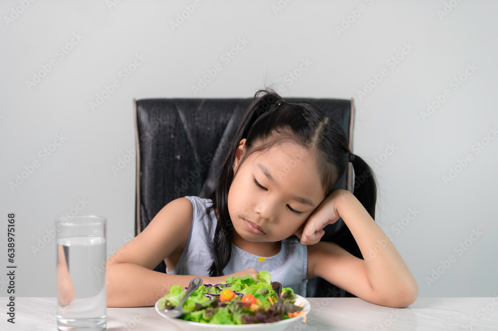 Little asian cute girl refuses to eat healthy vegetables.Nutrition & healthy eating habits for kids concept.Children do not like to eat vegetables. Little asian cute girl refuses to eat healthy vegetables.Nutrition & healthy eating habits for kids concept.Children do not like to eat vegetables.