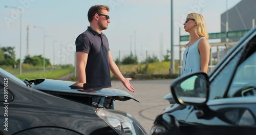 Man and woman drivers shake hands after a small road accident. In the foreground there are two cars. Happy ending a small road accident. Car insurance. photo