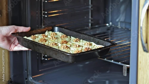 Baklava. The woman opens the oven and puts the pan with baklava for baking
