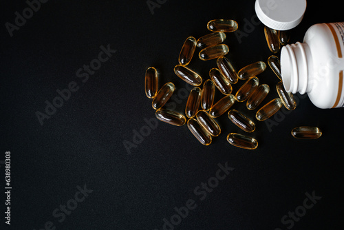 Fish oil capsules with jar on black background