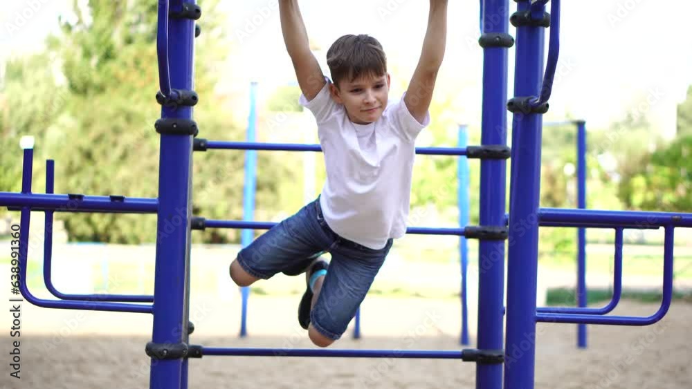 a nine-year-old boy swings while hanging on a horizontal bar. a nine-year-old boy swings while hanging on a horizontal bar.