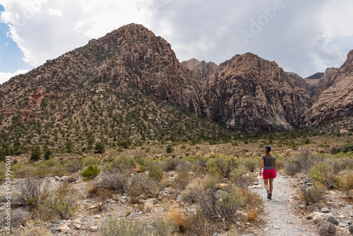 Photography Woman on Ice Box Canyon Trailhead hiking path with scenic view of rugged Spring Mountain range in Red Rock Canyon National Conservation Area in Mojave Desert near Las Vegas, Nevada, USA