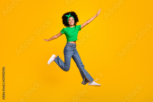Full size photo of excited energetic person jumping arms wings flying empty space isolated on yellow color background