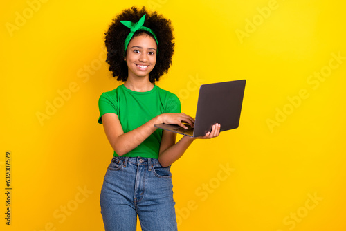 Photo of friendly cute girl toothy smile hold use wireless netbook elearning isolated on yellow color background