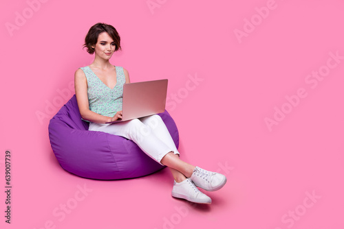 Full body photo of young girl sit bean bag dorm room using new netbook apple device marketing analytic isolated on pink color background