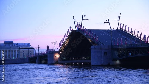 Side view of opening bascule bridge at twilight (early morning) in Saint Petersburg city, Russia. Transportation uilding. Real time video. Russian text on flags translation: fire department. photo