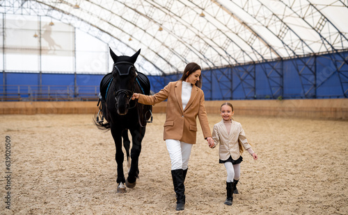 Horseride woman jockey with girl. Woman jockey trainsher horse.