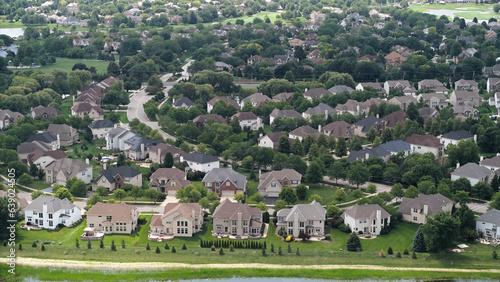 Above aerial shot of trees and residential houses and yards near city . 