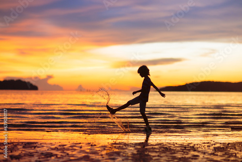 Child playing on ocean beach. Kid at sunset sea. © famveldman