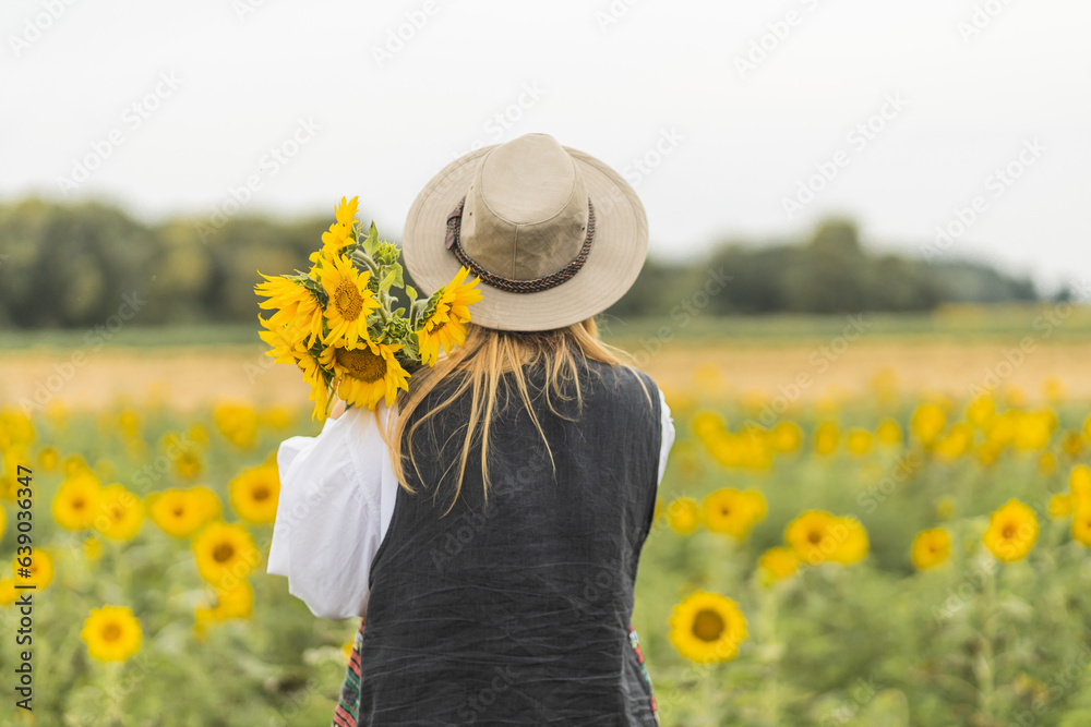 A girl in a field with sunflowers rejoices and enjoys life. A walk in a sunflower field. Agriculture. Rural life on the farm. The girl holds sunflower flowers in her hands.
