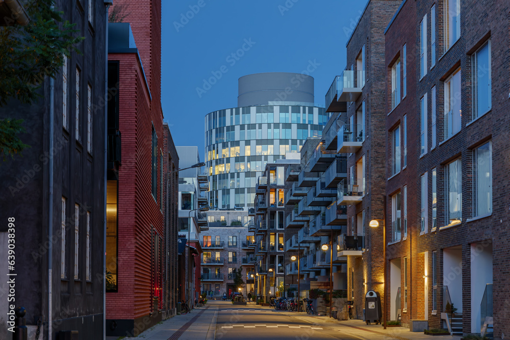 Outdoor night street diminishing perspective view among residential buildings toward famous office building 