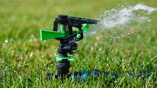 Automatic sprinkler system watering the lawn on a background of green grass.