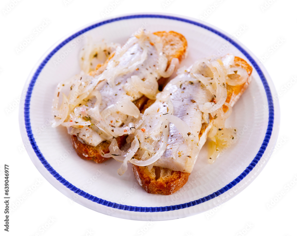 Slices of fresh wheat bread with crispy crust topped with pickled herring fillet and sliced marinated onions. Popular savory and tangy snack. Isolated over white background