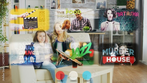 Quadro em tela Mother and daughter watching entertaining content on holographic projector, relaxing at home on sofa enjoying time together on lazy day