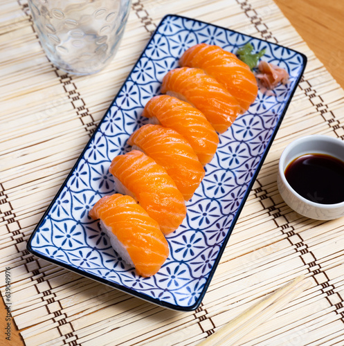 Sake nigiri - tasty dietary sushi with salmon and tuna, soy sauce closeup