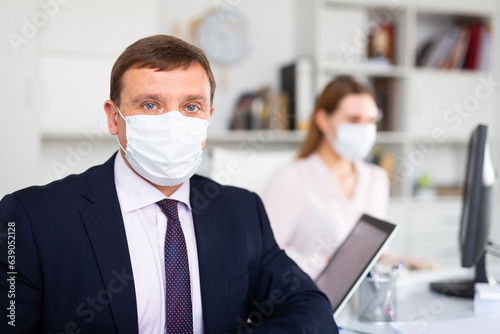 Portrait of adult businessman in protective medical mask at office