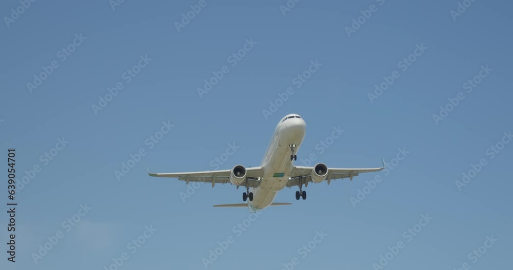 A commercial jet flying through a clear blue sky with fluffy white clouds