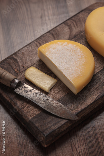 Portuguese cheese on board on wooden background, old knife