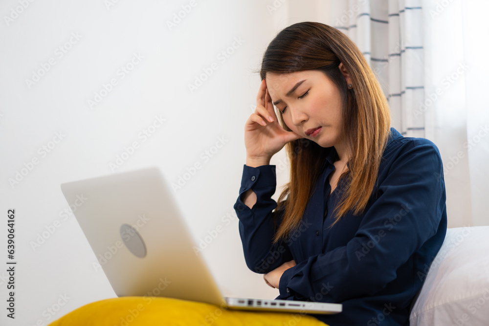 Overworked Asian woman using a laptop working on the bed at home Overworked Asian woman using a laptop working on the bed at home