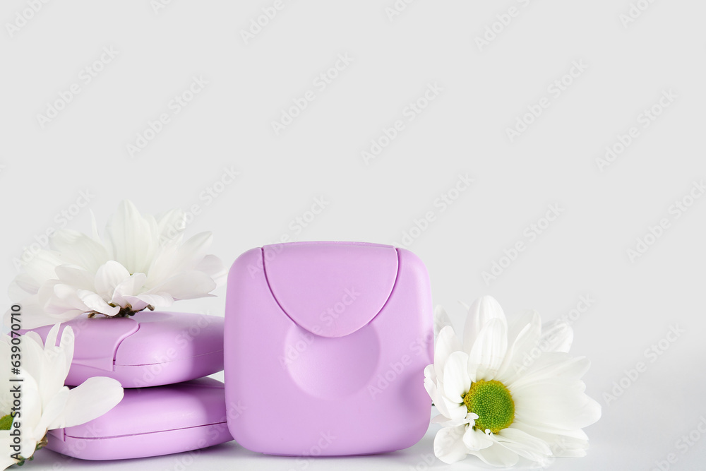 Tampons storage boxes and chamomile flowers on white background