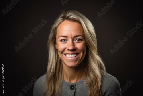 Portrait of a beautiful blond woman smiling at the camera on a black background