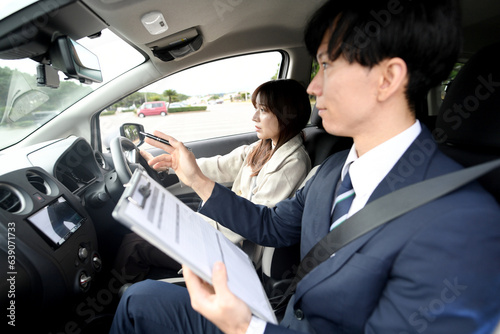 車の運転教習をする男性教官と女性生徒  © koumaru