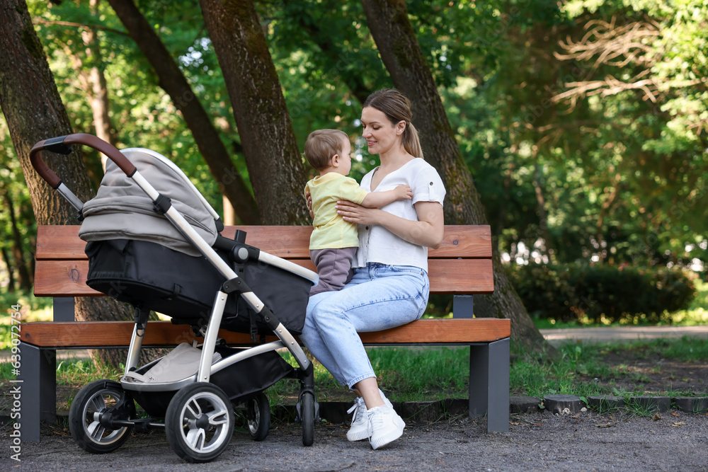 Happy nanny with cute little boy on bench in park Happy nanny with cute little boy on bench in park