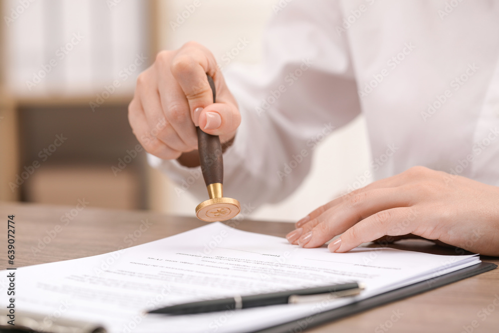 Woman stamping document at table, closeup view Woman stamping document at table, closeup view