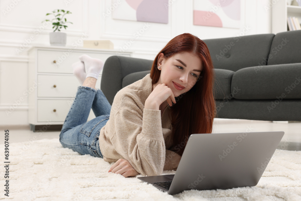 Fototapeta premium Beautiful woman with laptop on rug in living room