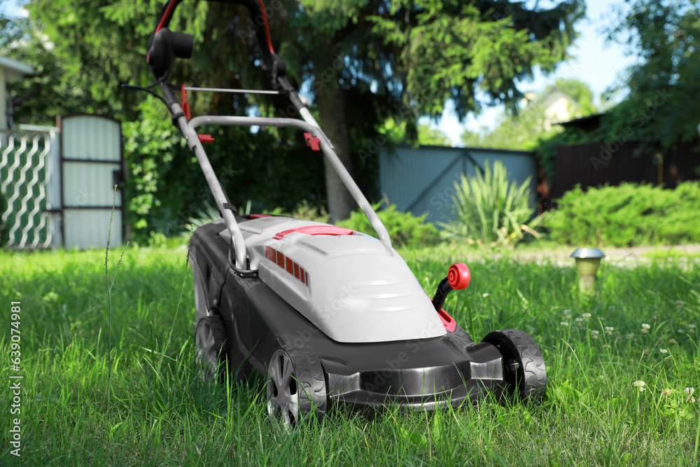 Fototapeta premium Lawn mower on green grass in garden
