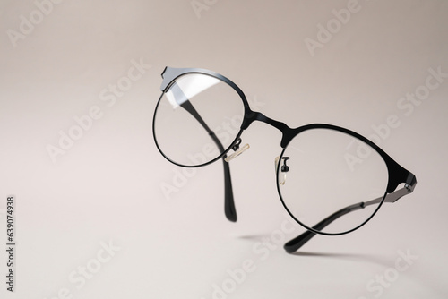 Stylish pair of glasses with black frame on beige background. Space for text