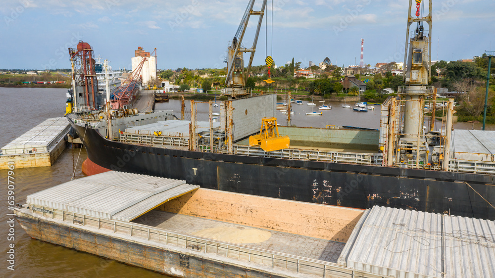 Self unloading bulk carrier cargo hatches open unloading sugar. Sugar is loaded onto barges and trucks. Aerial close up view of grab bucket.