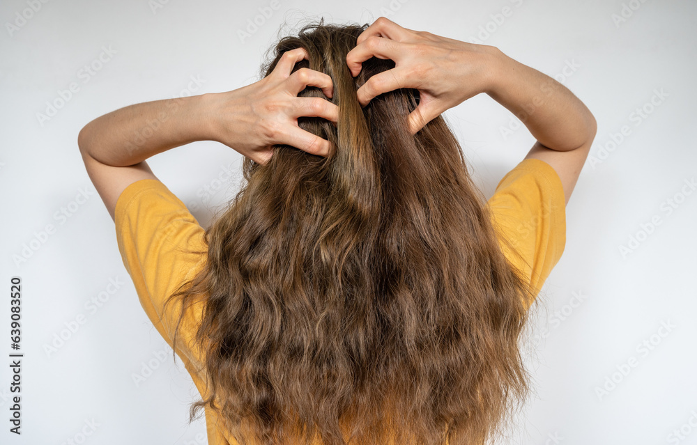 Obraz premium Rear view of young woman while scratching her scalp caused of itchy scalp.