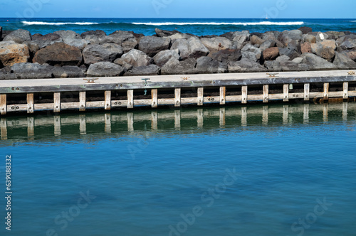Wooden Dock in a Harbor with Surf Breaking in the background.