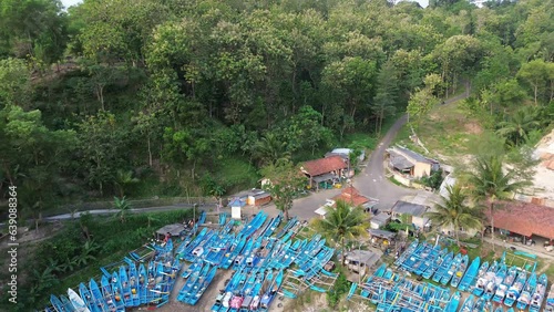 4k Aerial drone view of Pedalen Beach, Kebumen Indonesia with traditional boats that lean against beautiful waves and cliffs photo