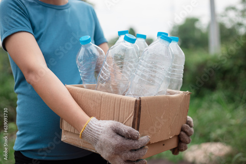 Plastic bottle in paper box. Woman sorting garbage, holding carton box full of plastic bottles for preserving saving environment nature protection. photo