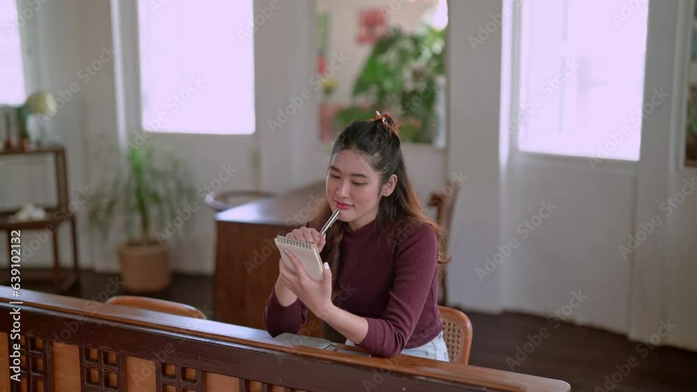 Confident Happy young Asian businesswoman Focused and sitting and taking notes In studio, Concept of remote work Confident Happy young Asian businesswoman Focused and sitting and taking notes In studio, Concept of remote work