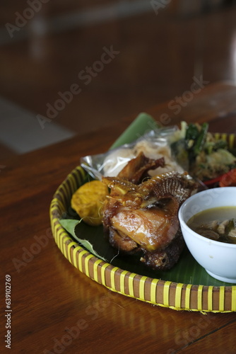 Traditional food on bamboo tray. fried chicken, vegetables, tofu and rice. Ayam goreng kampung photo