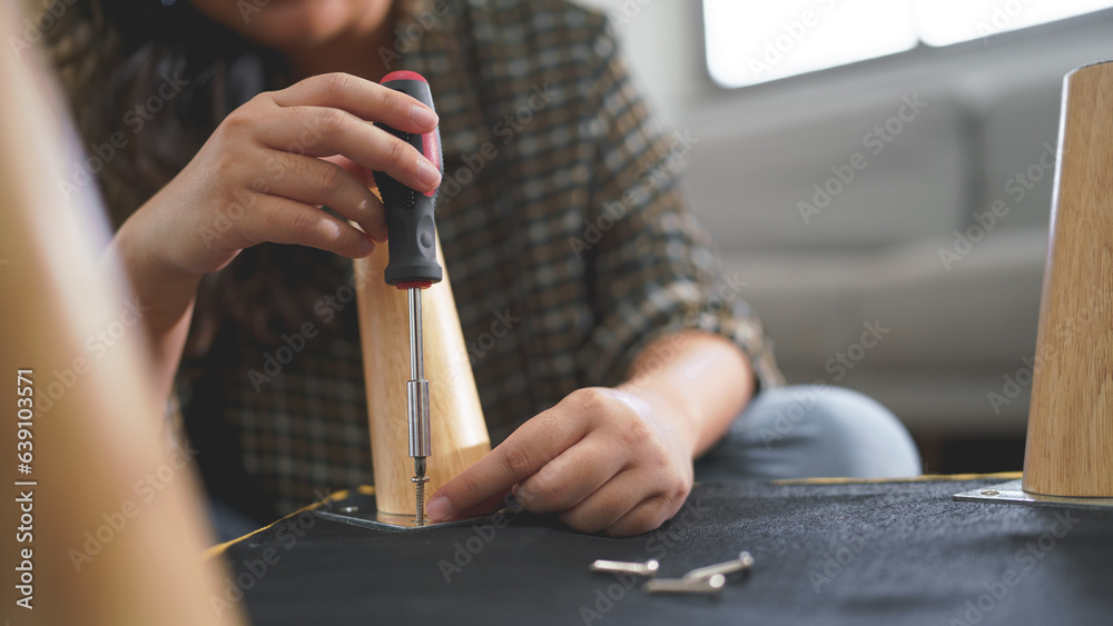 Women use screwdriver equipment to tighten screw while assembling leg of chair to making furniture - obrazy, fototapety, plakaty 
