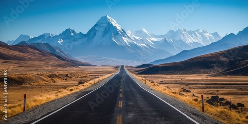 Empty country road by snowcapped mountains against clear blue sky